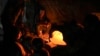 Раселени Палестинци седат до импровизирана печка во шатор во појасот Газа, 5 декември 2024 година