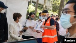 A staff member assists people waiting in line outside a coronavirus disease (COVID-19) vaccination center at Sydney Olympic Park during a lockdown to curb the spread of an outbreak in Sydney, Australia, Aug. 16, 2021. 