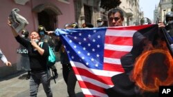 Prosvjednici protiv peruanskog predsjednika Martina Vizcarre, koji se suočava s opozivom, nose američku zastavu s slovom Q, pozivajući se na QAnon, u blizini Kongresa u Limi, Peru, 9. novembra 2020.