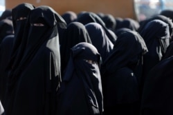 FILE - Women stand together at the al-Hol displacement camp in Syria, April 2, 2019.