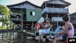 Women wash clothes at the Amazon river in Leticia, Colombia, on May 13, 2020, amid the new coronavirus pandemic. 