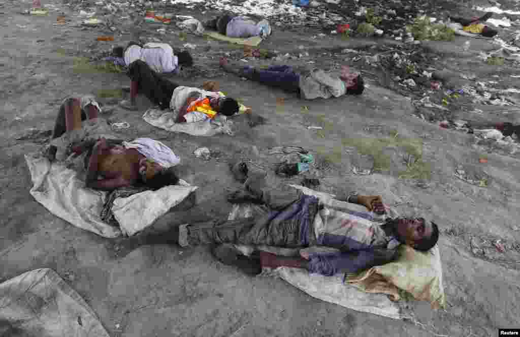 People sleep on the Yamuna River bed under a railway bridge during a hot summer day in the old quarter of Delhi, India, May 31, 2015. 