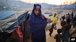 A Rohingya woman holds a vessel for drinking water at Palangkhali refugee camp in Cox's Bazar, Bangladesh, Wednesday, Oct. 4, 2017. More than half a million Rohingya have fled from Myanmar to Bangladesh in just over a month