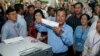 In this Sunday, July 29, 2018, file photo, Cambodian Prime Minister Hun Sen, center, of the Cambodian People's Party (CPP), holds a ballot before voting at a polling station in Takhmua in Kandal province, southeast of Phnom Penh, Cambodia. 