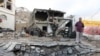 Men stand next to a crater made by a car bomb attack near the presidential palace in the southern port city of Aden, Yemen, Jan. 28, 2016. 