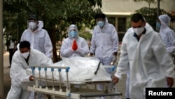 Kerabat bereaksi ketika petugas kesehatan menarik tandu yang membawa tubuh seseorang yang meninggal karena COVID-19, di kamar mayat di Ahmedabad, India, 8 Mei 2021. (Foto: Reuters)