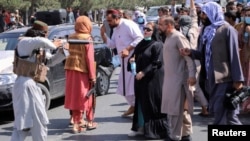 Seorang anggota Taliban tampak menodongkan senjata ke arah seorang wanita dalam sebuah demonstrasi yang menyuarakan gerakan anti-Pakistan. Demonstrasi dilakukan di dekat kedutaan Pakistan, di Kabul, Afghanistan, pada 7 September, 2021. (Foto: Reuters/Stringer)