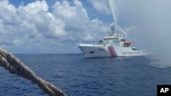 FILE - In this Sept. 23, 2015, file photo, Chinese Coast Guard members approach Filipino fishermen as they confront each other off Scarborough Shoal in the South China Sea, also called the West Philippine Sea. 