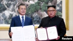 문재인(왼쪽) 한국 대통령과 김정은 북한 국무위원장이 지난 2018년 9월 19일 평양 백화원 영빈관에서 평양공동선언문에 서명한 뒤 기념촬영하고 있다. (자료사진)