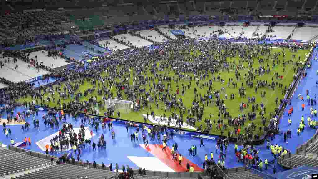 Après que trois explosions ont retenti aux abords du Stade de France vendredi 13 novembre 2015, les spectateurs ont envahi le terrain en attendant d'être évacués en toute sécurité. 