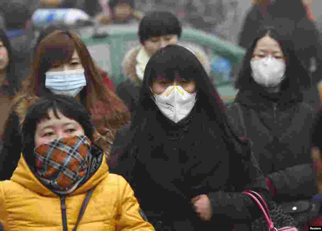 Commuters wearing masks make their way amid thick haze in the morning in Beijing, Feb. 26, 2014. 