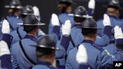 FILE - Members of the Massachusetts State Police 90th Recruit Training Group raise their hands as they are sworn in as State Police Troopers by Mass. Gov. Maura Healey, not shown, during ceremonies, Oct. 9, 2024, at the DCU Center, in Worcester, Mass.