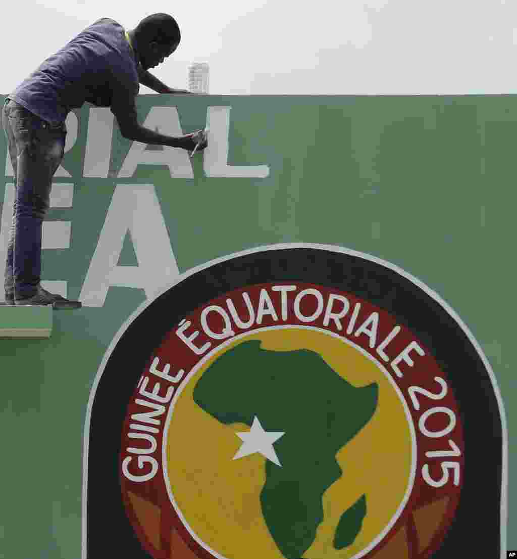 Un traveilleur passe un coup de peinture sur les écrits peints du mur avant l'ouverture de la Coupe d'Afrique des Nations samedi au stade de Bata, en Guinée équatoriale, le vendredi 16 janvier 2015.