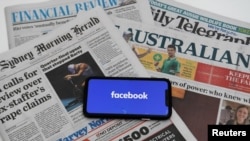 El logo de Facebook en una pantalla de celular sobre copias de diarios australianos, en Canberra Australia, este jueves 18 de febrero.