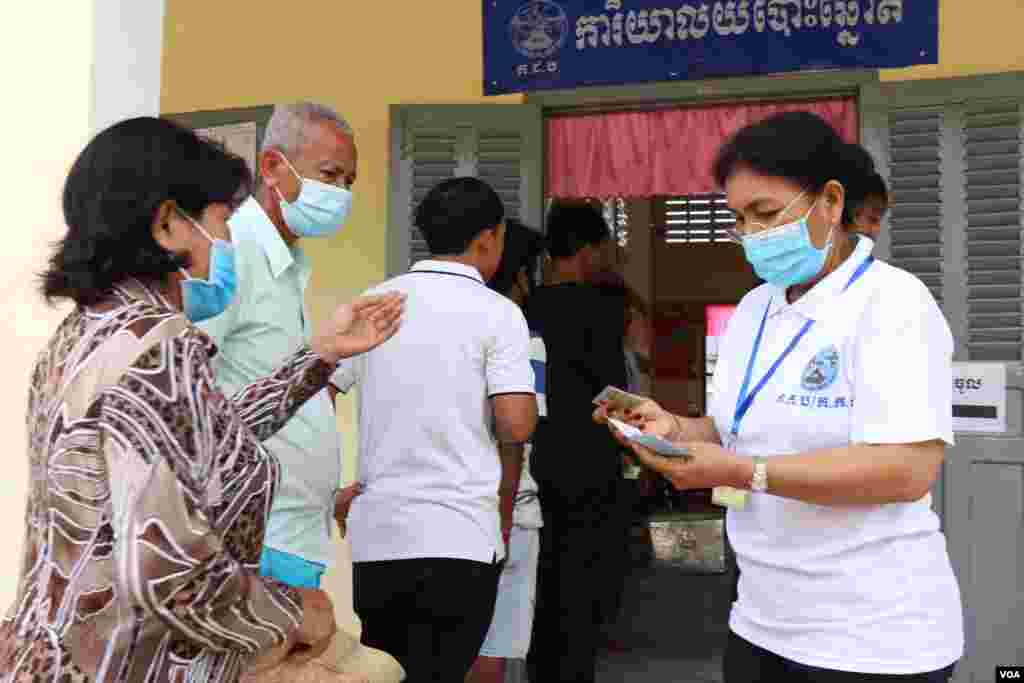 មន្ត្រីតាមការិយាល័យបោះឆ្នោត ត្រួតពិនិត្យឯកសារបោះឆ្នោតរបស់ពលរដ្ឋ នៅការិយាល័យបោះឆ្នោតអូរតាគាំ១ ក្នុងក្រុងបាត់ដំបង នៅថ្ងៃទី០៥ ខែមិថុនា ឆ្នាំ២០២២។ (លាស់ លីបលីប/វីអូអេ)