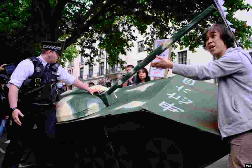 2022年6月4日參加六四事件33週年抗議的示威者抬著紙紮坦克從唐寧街首相府外遊行前往中國駐英大使館,在大使館外被倫敦警方攔截。(美國之音鄭樂捷)
