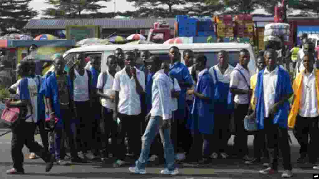 Une scène de gnes qui attendent un moyen de transport à Kinshasa. Une partie importante du transport est assurée par les conducteurs des taxi-motos accusés d'être des membres des gangs que la police a visés. (AP Photo/Saul Loeb, Pool)