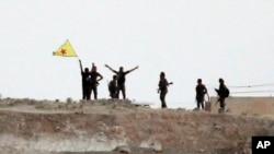 Kurd askarlari Suriyaning Tal-Abyad shahri yaqinida bayrog'ini ko'tarib turibdi. 15-iyun 2015-yil