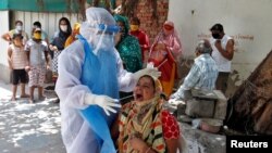 Seorang petugas medis mengenakan APD lengkap, melakukan test swab di kawasan permukiman penduduk di Ahmedabad, India, 22 Mei 2020.
