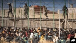 FILE: Riot police officers cordon off the area after migrants arrive on Spanish soil after crossing the fences separating the Spanish enclave of Melilla from Morocco in Melilla, Spain, June 24, 2022.