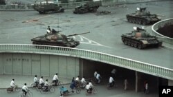 1989年6月6日星期二上午，在中國北京，天安門廣場大屠殺發生兩天後，自行車乘客稀少地穿過一條隧道，上面是天橋上部署的軍用坦克。 （美聯社資料照片）