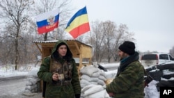 FILE - Pro-Russian rebels, cossacks from the 1st Cossack Regiment, guard a checkpoint decorated by Russian national and Don Cossacks flags, just outside in Pervomaisk, eastern Ukraine, Dec. 6, 2014.