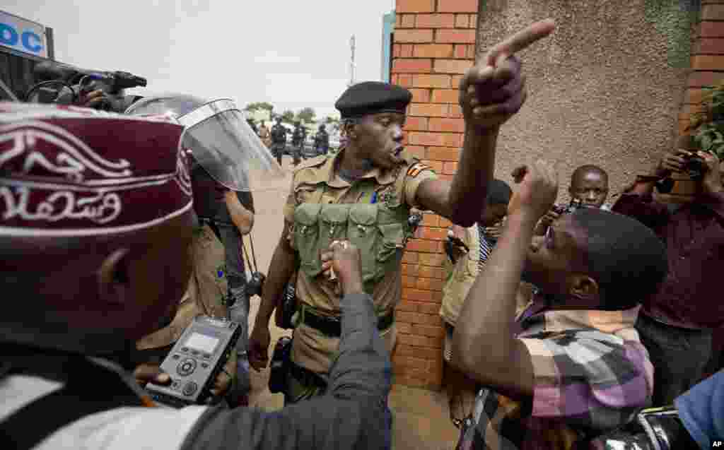 FILE - A policeman argues with a supporter of opposition leader Kizza Besigye at the gates of his party headquarters, before police who had surrounded it raided the building, in Kampala, Uganda, Feb. 19, 2016.