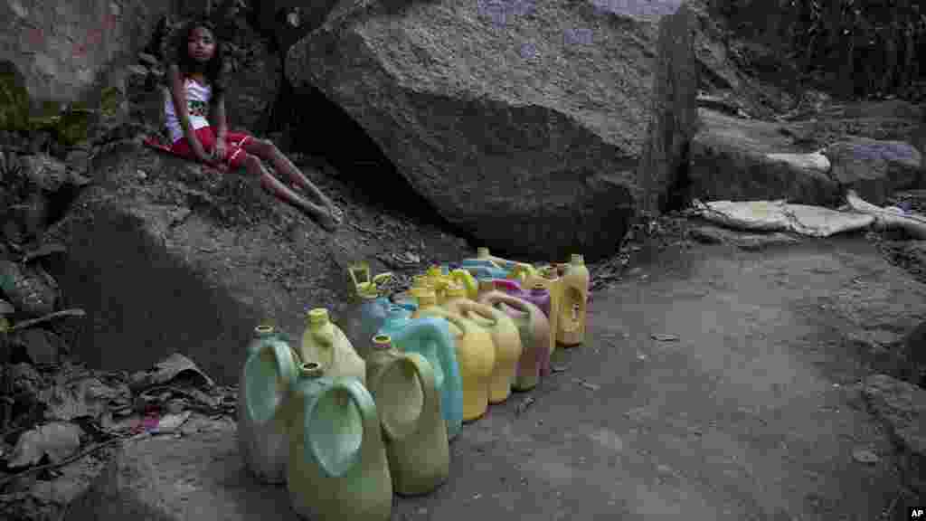 Une petite fille attend l'arrivée de l'approvisionnement de eau à un robinet public à Gauhati, Inde, le 21 mars 2017.