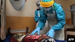 Un médecin de la Sierra Leone soigne une patiente dans la quarantaine installée pour contenir l'épidémie, à Kenema, le 7 février 2011.