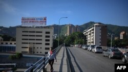 Autos hacen fila cerca de una gasolinera junto a un cartel del Partido Socialista Unido de Venezuela (PSUV), en Caracas, el 27 de junio de 2023. (Federico PARRA / AFP)