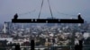 Trabajadores de la construcción viajan sobre una viga que cuelga de una grúa en el sitio de construcción de un edificio residencial de gran altura en la Ciudad de México, el 17 de junio de 2022.