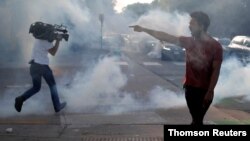 Un manifestante discute con un policía mientras un reportero dispar de gas lacrimógeno durante una manifestación contra la muerte de George Floyd, en Saint Paul, Minnesota.
