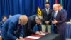 Los delegados jefe para las negociaciones del oficialismo y la oposición en Venezuela, Jorge Rodríguez (izq.) y Gerardo Blyde (centro), firman uno de los dos acuerdos parciales firmados en Barbados con la facilitación de Noruega, el martes 17 de octubre de 2023.