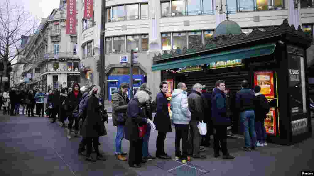 People queue to get a copy of satirical French magazine Charlie Hebdo new issue titled "Tout est pardonne" ("All is forgiven") showing a caricature of Prophet Mohammad in front of a kiosk in Paris, Jan. 14, 2015.
