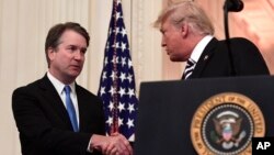 El presidente Donald Trump (derecha) estrecha la mano del juez de la Corte Suprema Brett Kavanaugh al iniciar la ceremonia simbólica de juramentación en el Salón Este de la Casa Blanca el lunes, 8 de octubre de 2018.