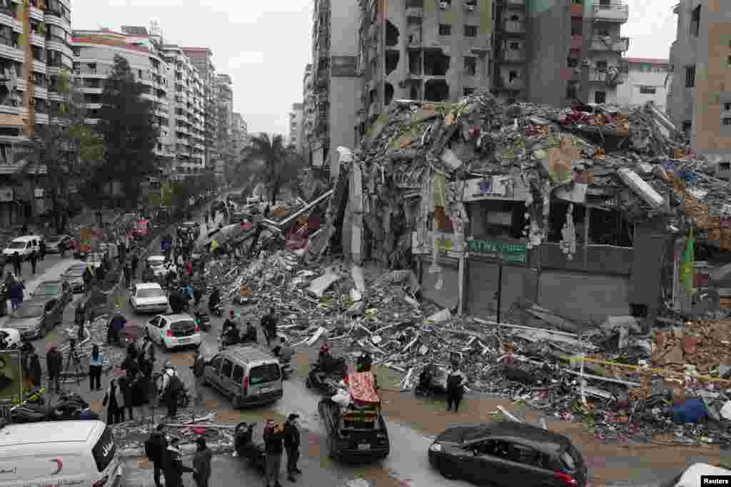 People gather as cars drive past rubble from damaged buildings in Beirut's southern suburbs, Lebanon, after a ceasefire between Israel and Iran-backed group Hezbollah took effect.