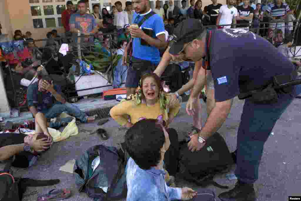 An Afghan refugee reacts after falling to the ground during scuffles between Greek police and refugees that protested over priority for a registration procedure at the port of Mytilene on the Greek island of Lesbos, Sept. 5, 2015.