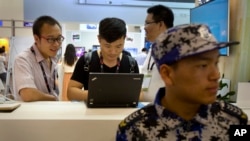 在全球移動互聯網大會上，一名與會者在會議保安身後使用電腦