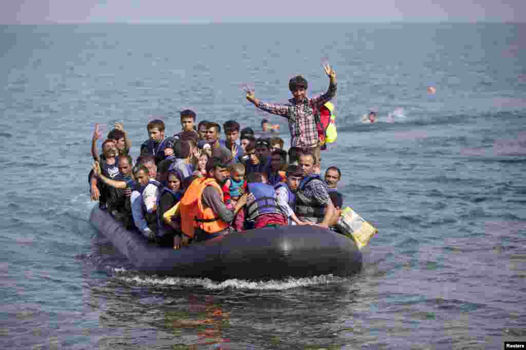 Syrian and Afghan refugees on a dinghy wave as they approach the Greek island of Lesbos, Sept. 3, 2015. The International Organization for Migration (IOM) says 1,500-2,000 are taking the route through Greece, Macedonia and Serbia to Hungary every day and that there is "a real possibility" the flow could rise to 3,000 daily.