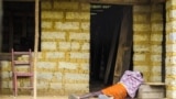 In this Tuesday, Oct. 21, 2014 file photo, a man suffering from the Ebola virus lies on the floor outside a house in Port Loko Community, on the outskirts of Freetown, in Sierra Leone. Ebola surveillance teams are going house-to-house in neighborhoods in 