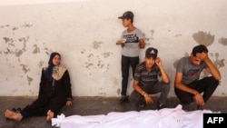 Pessoas choram o corpo de um ente querido morto durante os bombardeamentos israelitas contra o portão de segurança da sede da Agência das Nações Unidas de Assistência aos Refugiados da Palestina (UNRWA), no Hospital Batista, também conhecido como hospital árabe Al-Ahli.