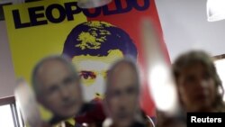 People hold portraits of opposition leader Antonio Ledezma in front of a wall with a portrait of opposition leader Leopoldo Lopez during a news conference at the Venezuelan coalition of opposition parties (MUD) headquarters in Caracas, Venezuela, Aug. 1, 2017.