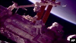 NASA astronauts Mark Vande Hei, left, and Scott Tingle work outside the International Space Station on Jan. 23, 2018, to give the robot arm a new hand. 