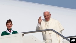 Paus Fransiskus melambaikan tangan ke arah wartawan di bandara internasional Fiumicino di Roma, Minggu (5/7) sebelum memasuki pesawat menuju Quito, Ecuador.