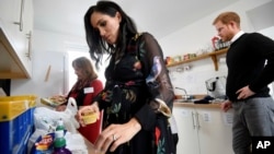 Pangeran Harry menyaksikan istrinya, Meghan Markle, menyiapkan paket-paket bantuan makanan saat mengunjungi dapur amal One25 di Bristol, Inggris, 1 Februari 2019.