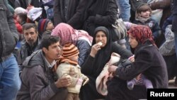 Syrians that evacuated the eastern districts of Aleppo rest while waiting to board buses, in a government-held area in Aleppo, Syria in this handout picture provided by SANA, Nov. 29, 2016.
