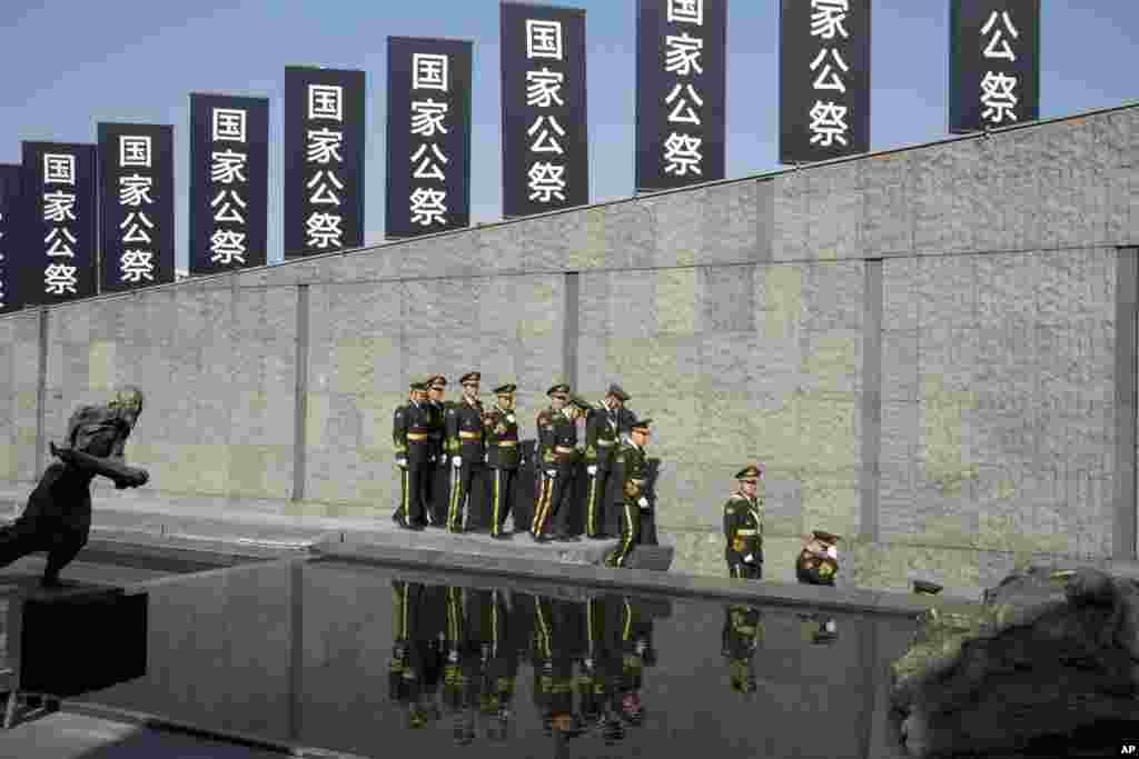 在南京举行的对于抗日战争中日本军队南京大屠杀公祭仪式之后,军人离开会场(2014年12月13日)。有日本官员质疑南京大屠杀是否曾经发生。这种否认态度多年来令北京愤怒,许多亚洲邻国感到,东京还没有足以偿还20世纪上半期到二战结束期间野蛮占领亚洲地区时所犯的战争罪行。