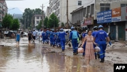 Petugas melakukan pembersihan di Gongyi, dekat Zhengzhou, provinsi Henan, China (22/7). 