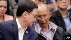 Former chief of the Philippine PNP-CIDG and now Mayor Benjamin Magalong, right, talks to Justice Secretary Menardo Guevarra at the resumption of the Senate probe Oct. 9, 2019 in suburban Pasay city south of Manila, Philippines. 