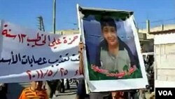 Demonstran anti-pemerintah Suriah membawa poster Hamza al-Khatib, anak laki-laki yang menjadi korban tewas kekerasan di Daraa.